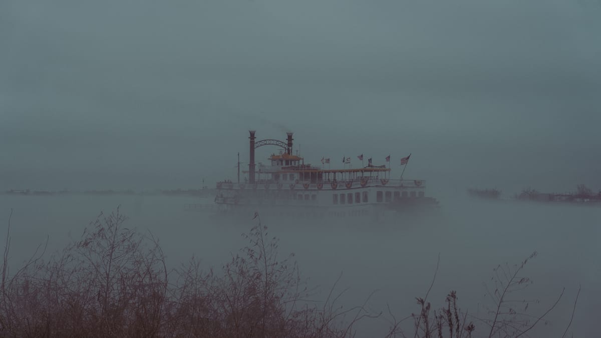 A vintage style photo of a Steamboat sailing along the Mississipi River, engulfed in fog.
